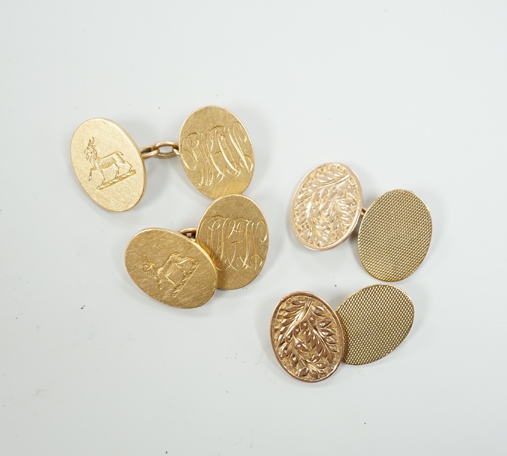 A pair of George V 18ct gold oval cufflinks, with engraved crest and initials, G.H. Johnstone & Co, Birmingham, 1915, 16.7 grams and a pair of late Victorian engraved 9ct gold oval cufflinks, 6.7 grams.